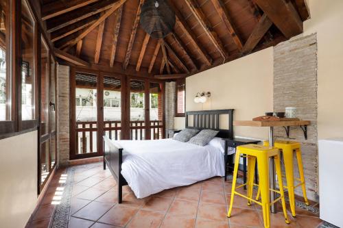 1 dormitorio con cama, mesa y taburetes amarillos en Urban Suites Granada, en Granada