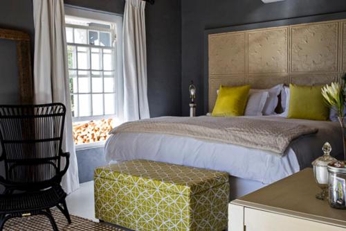a bedroom with a bed and a chair and a window at Olive Grove House in Prince Albert