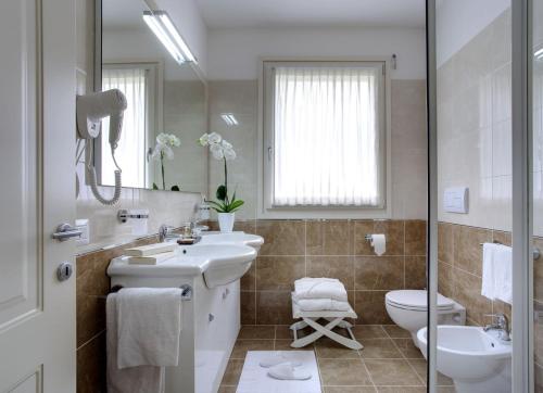 a bathroom with a sink and a toilet and a mirror at Grand Hotel Presolana in Castione della Presolana