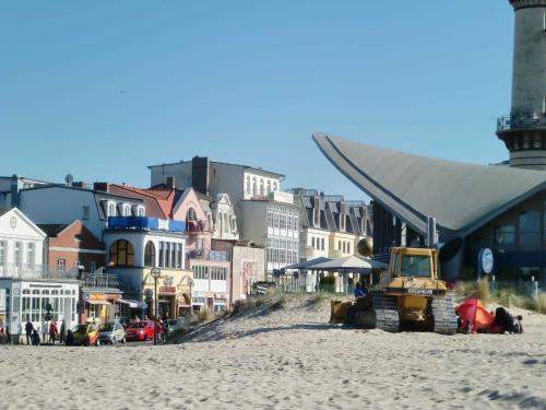een strand met een bulldozer op het zand en de gebouwen bij Ferienwohnung _ Kartenraum _ Objek in Warnemünde