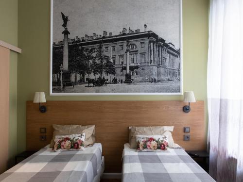 two beds in a room with a picture on the wall at Guest house Kolomna in Saint Petersburg