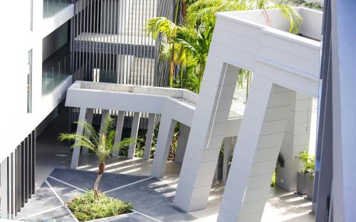 a white building with a palm tree in a courtyard at Absolute Twin Sands Resort & Spa - SHA Extra Plus in Patong Beach