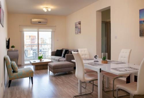 uma sala de estar com uma mesa e cadeiras e um sofá em Takelena Apartments em Limassol