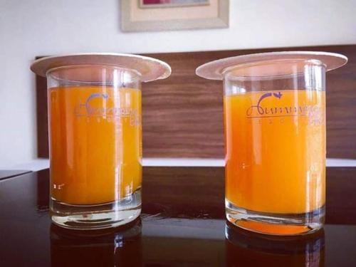 two glasses of orange juice sitting on a table at Hummingbird Resort in Mount Ābu