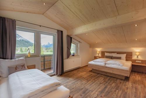 a bedroom with two beds and a large window at Ferienwohnungen stiLECHt in Elbigenalp