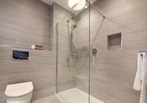 a bathroom with a toilet and a glass shower at Golflinks Hotel in Portrush