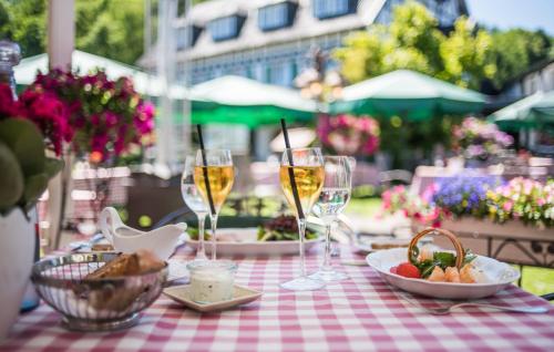 a table with glasses of wine and a plate of food at Lohmann's Romantik Hotel Gravenberg in Langenfeld