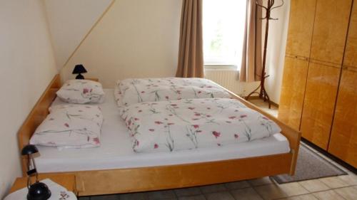 a small bedroom with a bed with a white comforter at Ruhige Unterkunft nahe der Nordsee in Friedeburg