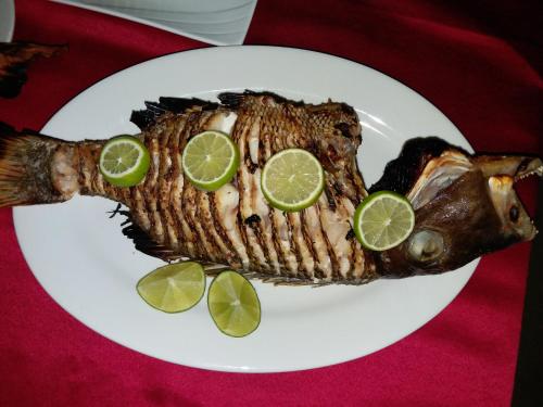 a fish on a plate with lime slices on it at Ras Rana Lodge in Rasdu