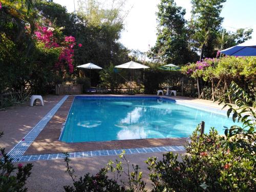 a swimming pool in a yard with trees and flowers at Mountain View Guesthouse in Sukhothai