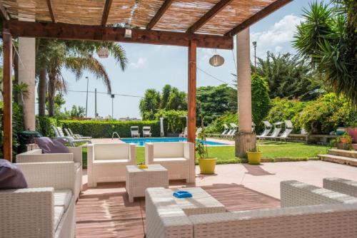 a patio with white chairs and a pool at Solemare Residence in Donnalucata