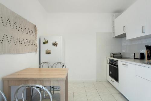 une cuisine avec des placards blancs et une table en bois dans l'établissement VIU Seaside Residence, à Sopot