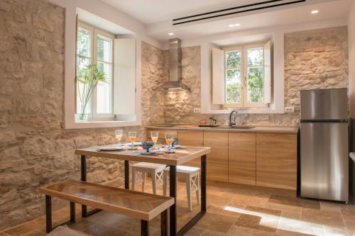 a kitchen with a wooden table and a refrigerator at Carpofoli Corfu Town Serviced Luxury Suites in Corfu
