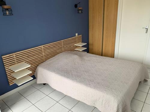 1 dormitorio con cama y pared azul en Le Saint Pierre, en Chemillé