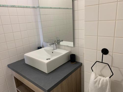 une salle de bain avec un lavabo blanc et un miroir dans l'établissement Le Saint Pierre, à Chemillé