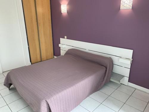 1 dormitorio con 1 cama con pared morada en Le Saint Pierre, en Chemillé