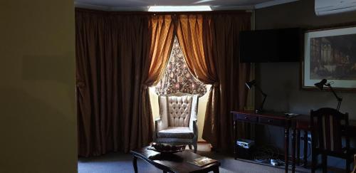 a living room with a chair in front of a window at Pietersburg Club in Polokwane