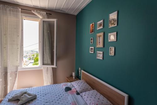 - une chambre dotée d'un mur bleu avec un lit et une fenêtre dans l'établissement Athina's house, à Thessalonique