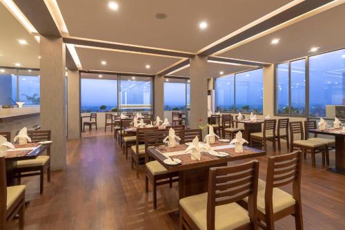 um restaurante com mesas e cadeiras e janelas grandes em Hotel Capital em Mandalay