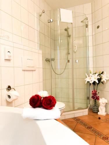 a bathroom with a shower and a red rose on a towel at Landhotel Restaurant Gärtner in Mücke