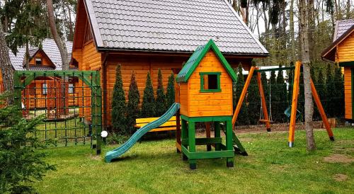 a small playground with a slide and a house at Zielone Domki in Pobierowo