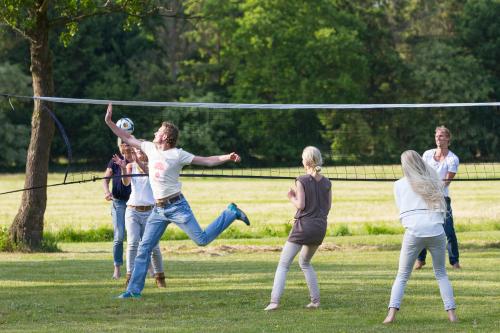 a group of people playing volleyball in a park at de Familieboerderij in Losser