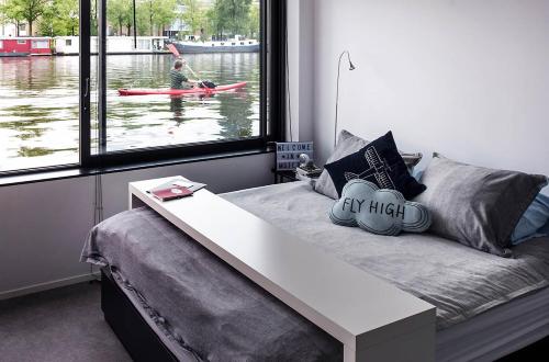 pokój z łóżkiem ze stołem i osobą w kajaku na zewnątrz w obiekcie Houseboat Amsterdam - Room with a view w Amsterdamie