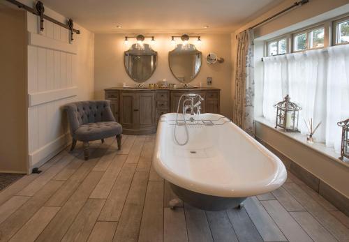 a bathroom with a tub and a chair and a sink at Holly Lodge Boutique B&B in Thursford