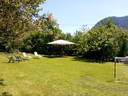 a group of chairs and an umbrella in a field at Baita Figliezzi in Castello Tesino