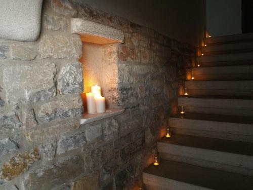 a room with a stone wall with candles and stairs at Archontika Karamarlis in Makrinítsa
