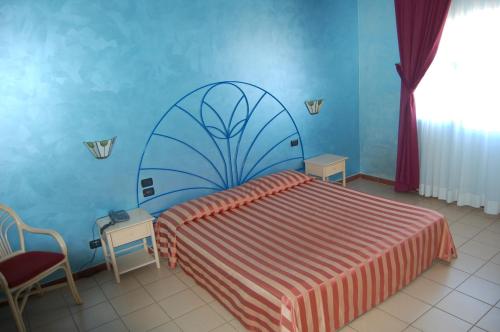 Marina di MelilliにあるHotel Club Pegasoの青い壁のベッドルーム1室(ベッド1台付)
