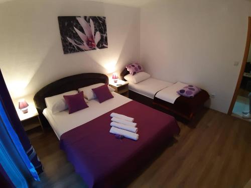 - une chambre avec 2 lits, des draps violets et des serviettes dans l'établissement Apartments Leža, à Neum