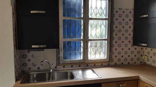una cucina con lavandino e due finestre di La Finestra sul Mare - Villa a Palumbo