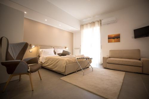 ein Schlafzimmer mit einem Bett, einem Sofa und einem Stuhl in der Unterkunft Prometeo rooms in Syrakus
