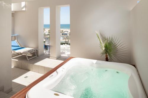 uma banheira na casa de banho com vista para o oceano em Hotel Ambassador em Rimini