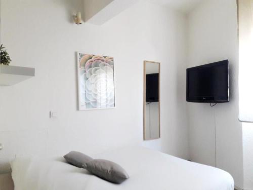 a white room with a bed and a flat screen tv at Studios Raphael in Saint-Raphaël