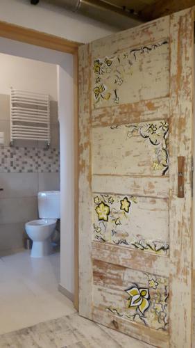 ein Badezimmer mit einem WC und einer Holztür in der Unterkunft Miodowy Kociołek in Mrągowo