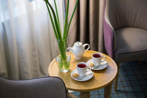 a table with two cups of coffee and a vase at Jump INN Hotel Belgrade in Belgrade