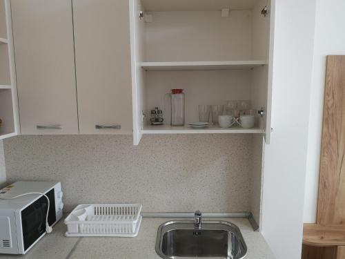 a kitchen counter with a sink and a microwave at Balchik Sea View Apartments in Princess Residence in Balchik