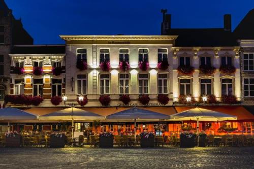 a building with tables and umbrellas in front of it at Grand Cafe Hotel de Bourgondier in Bergen op Zoom