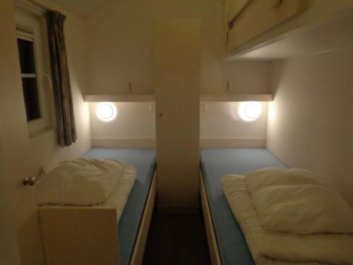 een kleine kamer met 2 bedden en 2 verlichting bij Lodge 6 personen camping de Molenhof in Reutum