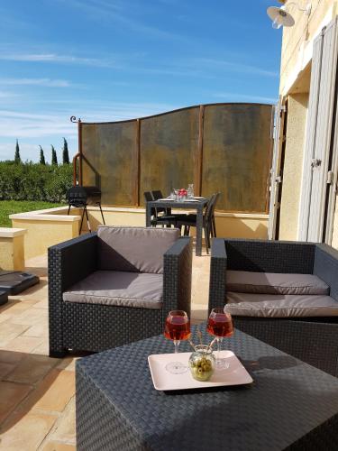 - une terrasse avec 2 canapés et 2 verres de vin dans l'établissement Le Mas Saint Jean, à Mézoargues