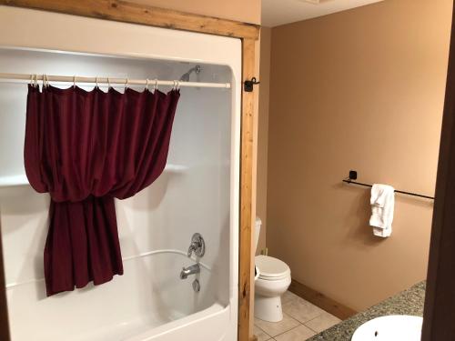 ein Badezimmer mit einer Badewanne und einer Dusche mit einem roten Vorhang in der Unterkunft Lakefront Townhouse Family Complex, Popular Wine Country and the Best Golfing in Osoyoos