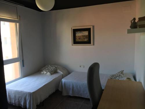 Cette chambre comprend 2 lits, une table et une fenêtre. dans l'établissement Piso céntrico 2 habitaciones cerca del mar, à Hospitalet de l'Infant