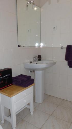 a white bathroom with a sink and a mirror at Gladmar Apartment in La Mata