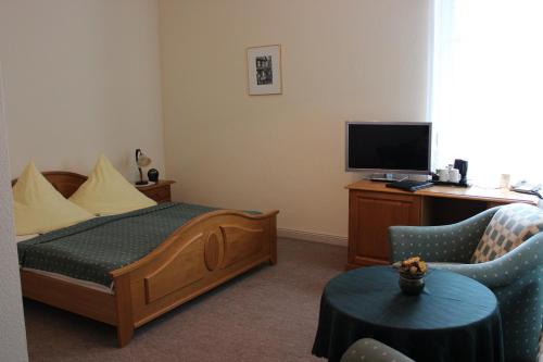 Schlafzimmer mit einem Bett, einem TV und einem Stuhl in der Unterkunft Villa Jagdhaus in Wernigerode