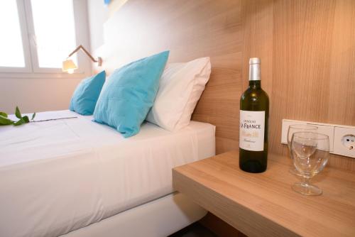 a bottle of wine sitting on a table next to a bed at Cala Llenya Resort Ibiza in Cala Llenya