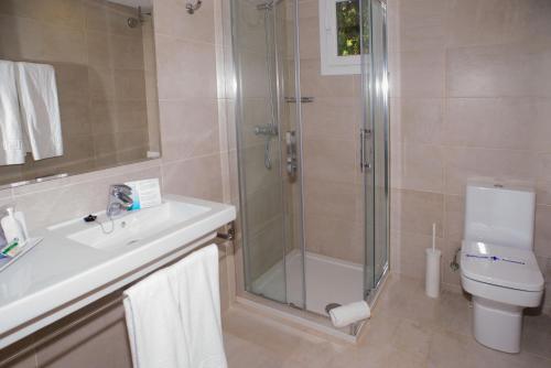 Un baño con ducha, lavabo e inodoro. en Cala Llenya Resort Ibiza, en Cala Llenya