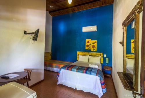 1 dormitorio con cama y pared azul en Pousada Pepalantus, en Serra do Cipo