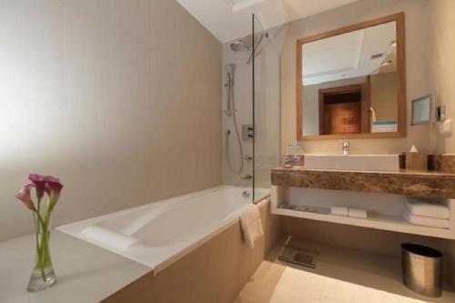 a bathroom with a tub and a sink and a mirror at Somewhere Hotel Al Ahsa in Al Hofuf
